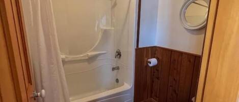 A bathroom with a bathtub, toilet, and shower curtain.