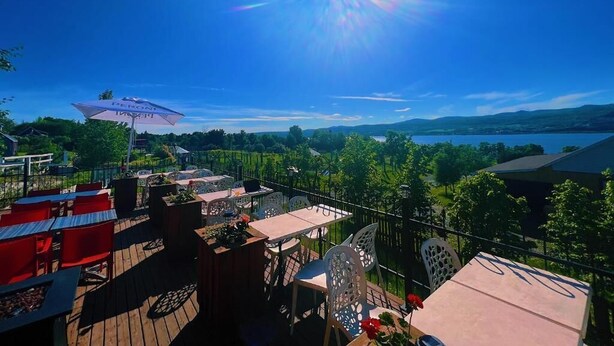 Una terraza con asientos al aire libre, vista a un lago y cielo despejado.