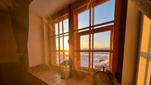 Una habitación con ventanas amplias, un banco de madera, un farol y un reloj.