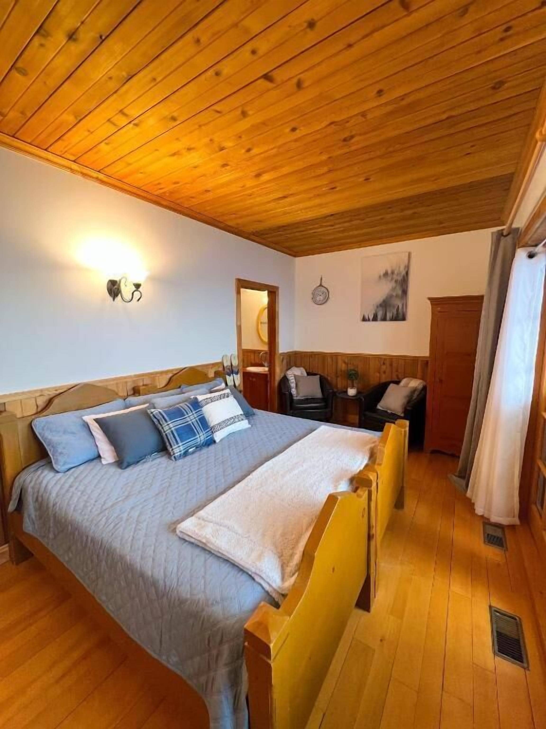 Une pièce aux murs lambrés, avec un lit, un bureau et une chaise.