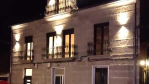 Ein zweistöckiges Gebäude mit einem Balkon, einer Tür und einem Fenster.