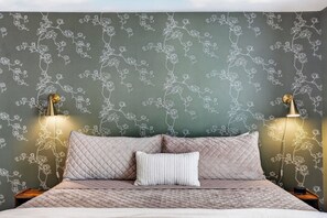 A bed with a quilted cover, two pillows, and a wall with floral wallpaper. - The Magnolia Collective- Pet Friendly , 2 Kings , Exercise Equipment (Lynchburg)