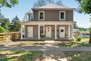 A two-story house with a front porch, a garage, and a fenced yard. - The Magnolia Collective- Pet Friendly , 2 Kings , Exercise Equipment (Lynchburg)