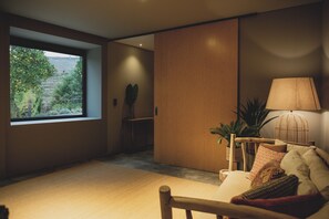 Una habitación con un ventanal grande, un sofá, una lámpara y una planta.