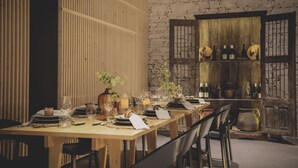 A dining table set with plates, glasses, and cutlery, flanked by chairs, in a room with a brick wall and wooden paneling. - The gateway to the magnificent Douro Valley. High-value wine tourism! (Santa Marta de Penaguião)
