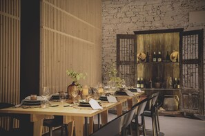 Una mesa de comedor preparada con platos, vasos y velas, rodeada de sillas.