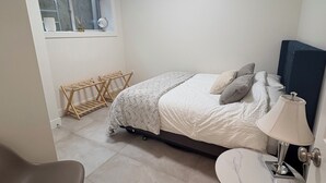 A bedroom with a bed, bedside table, chair, and a window with a view. - Peaceful Private Suite in Beautiful Home. 20 min to downtown (Burnaby)