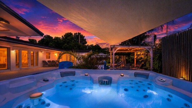 A hot tub area with a sunset view, outdoor seating, and a covered patio. - Villa Velvet ~ Heated Pool, Jacuzzi, Game Room & Minutes to Beaches (Pembroke Pines)