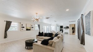 A spacious living room with a sofa, a coffee table, and a modern chandelier. - Villa Velvet ~ Heated Pool, Jacuzzi, Game Room & Minutes to Beaches (Pembroke Pines)