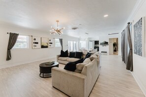 A spacious living room with a sofa, a coffee table, and a modern chandelier. - Villa Velvet ~ Heated Pool, Jacuzzi, Game Room & Minutes to Beaches (Pembroke Pines)
