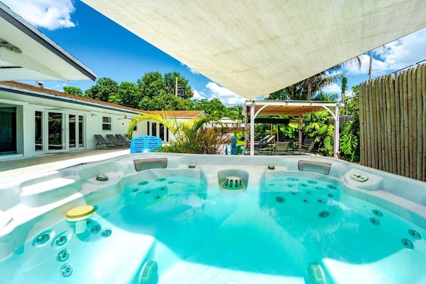A hot tub in a backyard with a pergola, lounge chairs, and a bamboo fence. - Villa Velvet ~ Heated Pool, Jacuzzi, Game Room & Minutes to Beaches (Pembroke Pines)