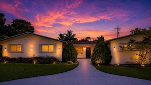 A two-story house with a driveway leading to the front door, surrounded by well-maintained lawns and trees. - Villa Velvet ~ Heated Pool, Jacuzzi, Game Room & Minutes to Beaches (Pembroke Pines)