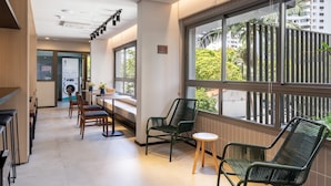 A modern hotel lobby with a seating area, large windows, and a view of the outside. - Studio Novo Campo Belo Piscina Congonhas Moema (São Paulo)