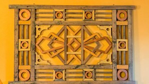 Pedaço de arte em madeira com padrão geométrico em forma de diamante no centro.
