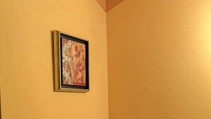Quarto nos fundos com uma mesa, duas cadeiras, um radiador e um quadro na parede.