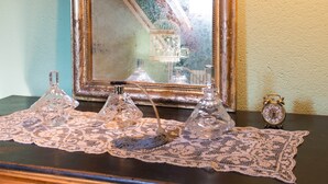 Une table ornée d’un chemin de table en dentelle, de trois vases en verre et d’une petite horloge.