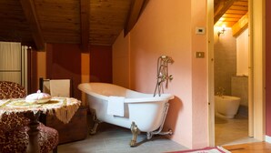A room with a clawfoot bathtub, a wooden ceiling, and a door leading to a bathroom. - Bizet Suite: Passion and Charm in "Red" (Villair-Amerique)
