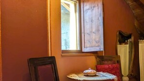 A room with a wooden ceiling, a window, a chair with a cushion, and a small table with a decorative item. - Bizet Suite: Passion and Charm in "Red" (Villair-Amerique)