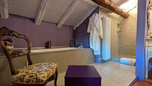 Een badkamer met een badkuip, douche en een houten stoel.
