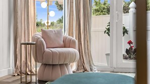Une pièce comprenant un fauteuil confortable, une petite table d’appoint et une vue sur l’extérieur, visible à travers une porte vitrée.