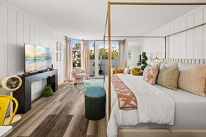 Ein Schlafzimmer mit Bett, Fernseher, Schreibtisch und Blick ins Freie.