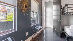 Une chambre moderne avec un lit superposé, un miroir fixé au mur et une fenêtre donnant sur des immeubles.