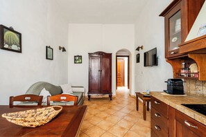 A kitchen with a wooden cabinet, a dining table, and chairs. - Cozy apartment near the port of Trapani and the city beaches (Trapani)