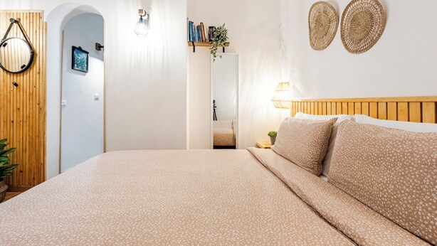 A bedroom with a bed, wooden headboard, wall-mounted decor, and a hallway leading to another room. - Cozy apartment near the port of Trapani and the city beaches (Trapani)