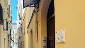 A narrow street with yellow buildings, a closed door, and a sign indicating '7 floors.' - Cozy apartment near the port of Trapani and the city beaches (Trapani)