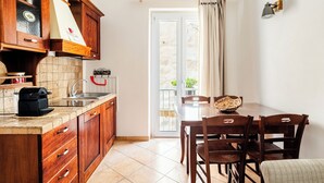 A kitchen with wooden cabinets, a sink, and a dining area with a table and chairs. - Cozy apartment near the port of Trapani and the city beaches (Trapani)