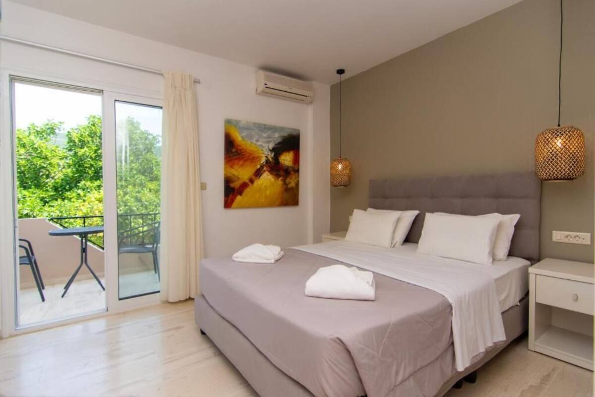 A bedroom with a bed, a painting, a nightstand, and a view of a balcony.