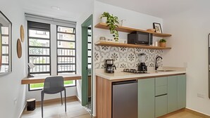 A compact kitchen with a built-in dishwasher, a coffee maker, and a microwave on a shelf. - Casa Velasquez 101 (Medellín)