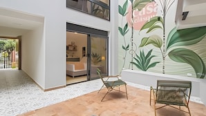 A modern interior with a large wall mural, a seating area, and a visible entrance to a room with a bed and a desk. - Casa Velasquez 101 (Medellín)