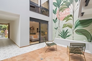 A modern interior with a large wall mural, a seating area, and a visible entrance to a room with a bed and a desk. - Casa Velasquez 101 (Medellín)