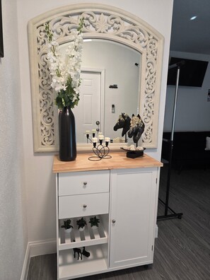 Un tocador con espejo, un florero y objetos decorativos.