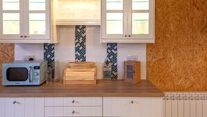 A kitchen with white cabinets, a microwave, a toaster, and a patterned backsplash.