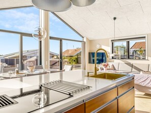 Eine moderne Küche mit großen Fenstern, einer zentralen Kochinsel und Blick auf die Nachbarschaft.