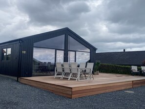 Ein modernes Gebäude mit einer Terrasse, großen Fenstern und der Hausnummer 12.