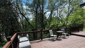 Una terraza de madera con una parrilla, sillas y una mesa.