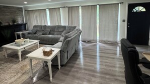 Un salón espacioso con un sofá gris, una mesa de centro y una silla de oficina negra.