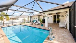 A swimming pool with a glass ceiling, lounge chairs, and a decorative seahorse statue. - Stylish Seahorse Villa in Cape Coral with Heated Pool (Cape Coral)