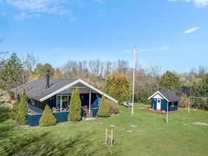 Ein zweistöckiges Haus mit einer großen Veranda, einer Fahnenstange und einem kleinen Anbau.