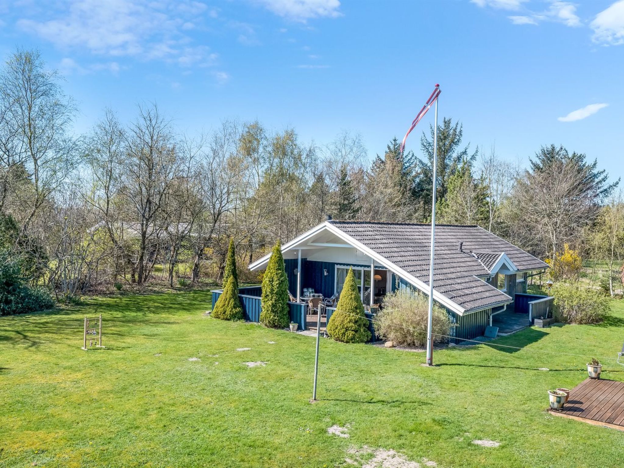 Une maison avec un toit en pente, une véranda et un mât pour drapeau.