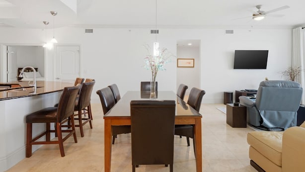 A modern kitchen with a dining area, a flat-screen TV, and a ceiling fan. - Mustique 2001 (Gulf Shores)