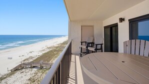 A balcony with a view of the beach, a table, and two chairs. - Ocean Breeze West 705 (Pensacola)