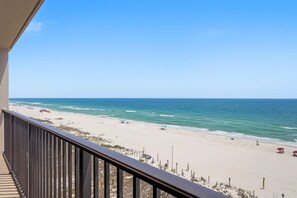 A beach view from a balcony with a railing, sandy beach, and ocean. - Ocean Breeze West 705 (Pensacola)