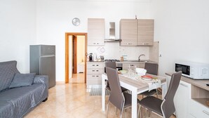 A compact kitchen with a dining area, a sofa, and a microwave. - Casa Alessia by Rentbeat (Cisternino)