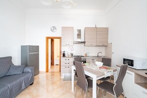 A compact kitchen with a dining area, a sofa, and a microwave. - Casa Alessia by Rentbeat (Cisternino)