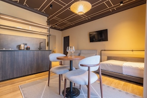 Habitación de hotel moderna con kitchenette, una cama y dos sillas.
