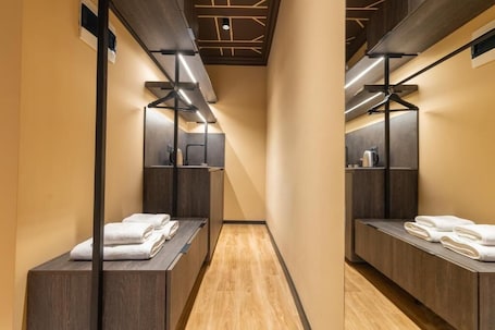 A modern bathroom with wooden flooring, dark cabinetry, and mirrors.